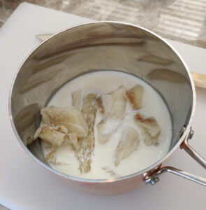 Stockfisch in Milch, Wasser, Zwiebeln, Knoblauch kochen